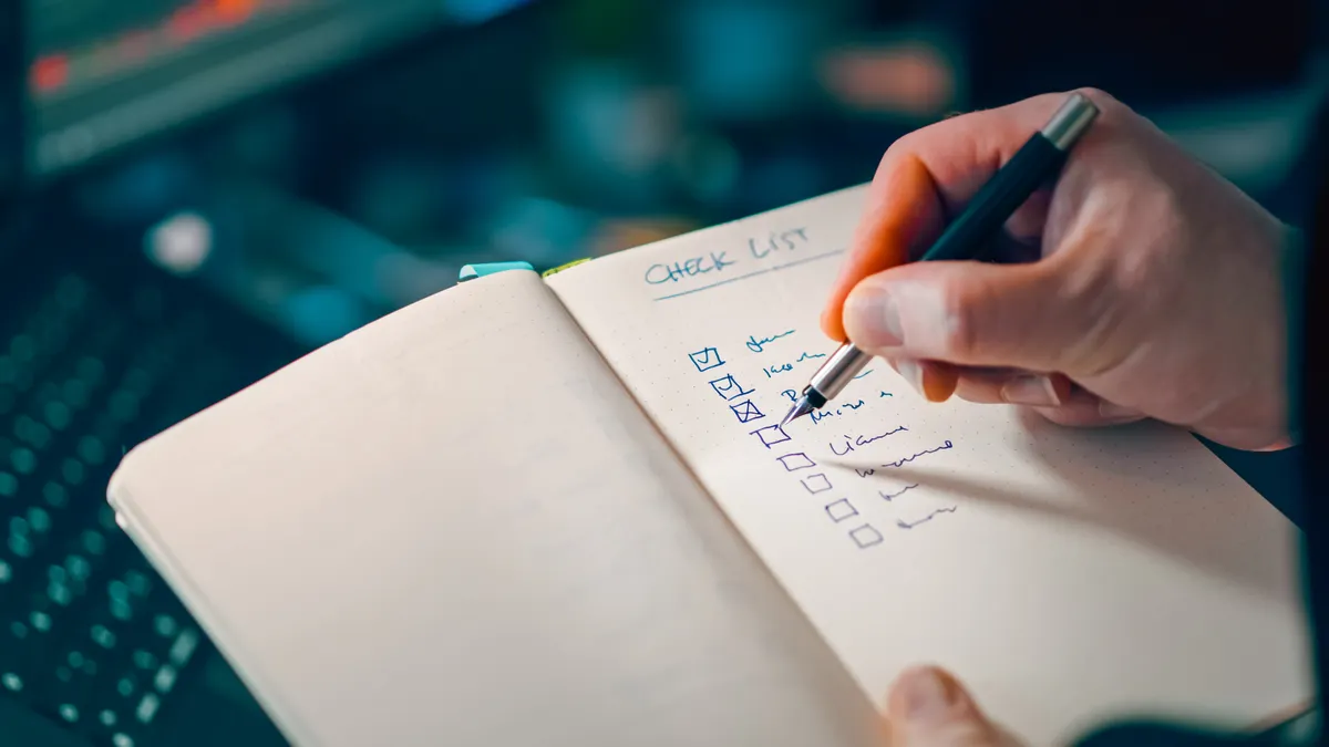 Hand checking off a written checklist in a notebook