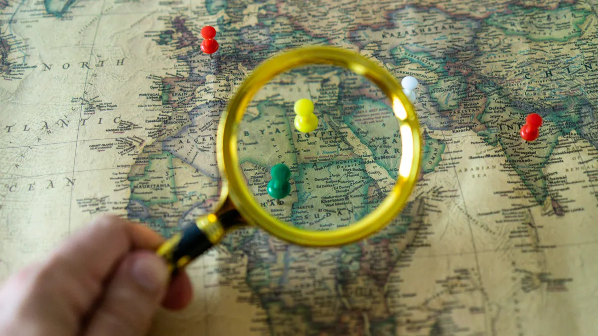magnifying glass over a map with colored push pins