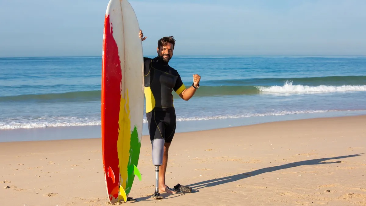 Surfer SEO review for content optimization — Content male surfer amputee standing near surfboard on sandy beach